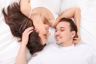 Happy couple spending time together on bed at home, top view