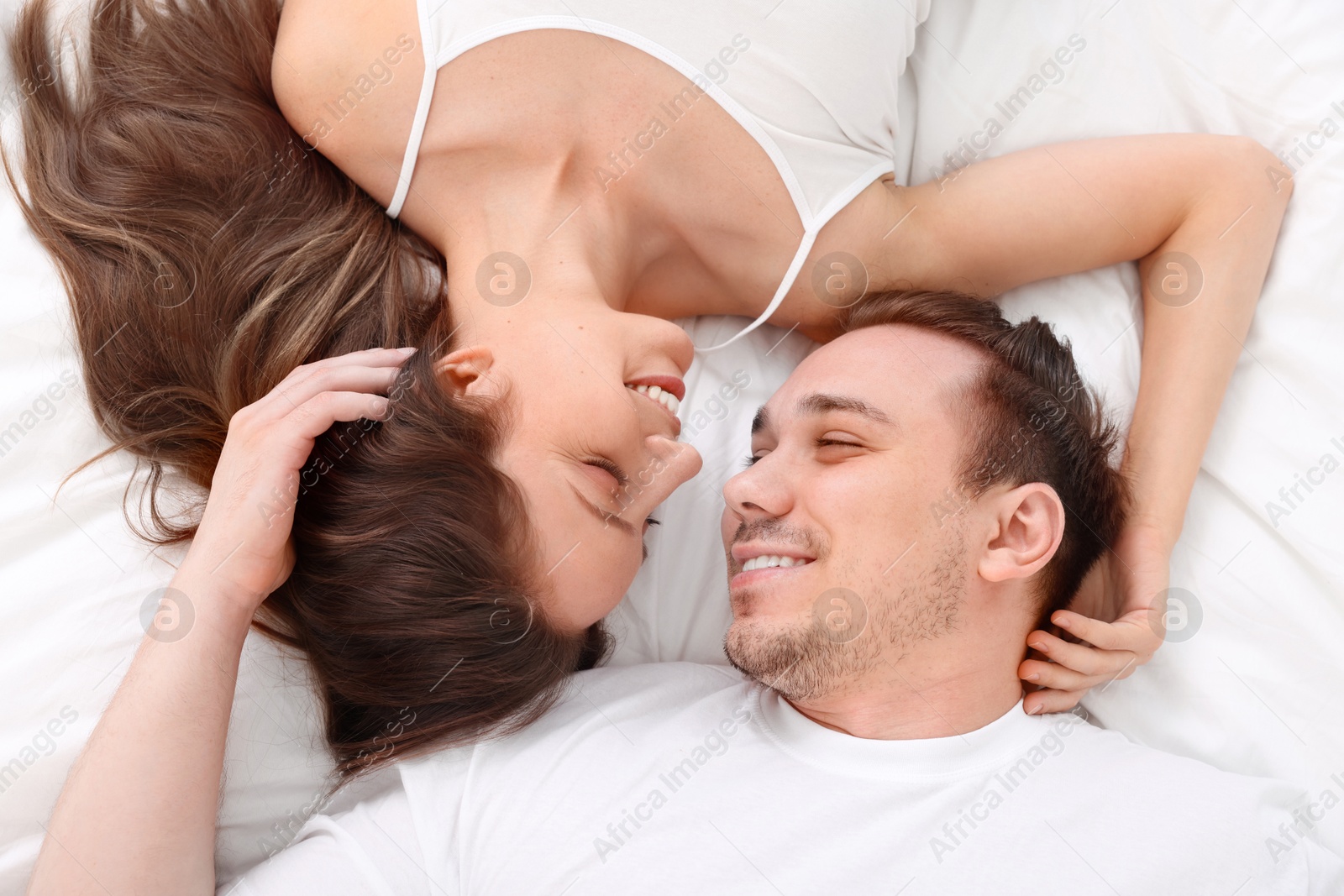 Photo of Happy couple spending time together on bed at home, top view