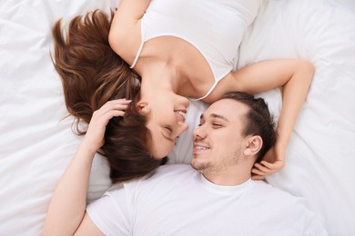 Photo of Happy couple spending time together on bed at home, top view