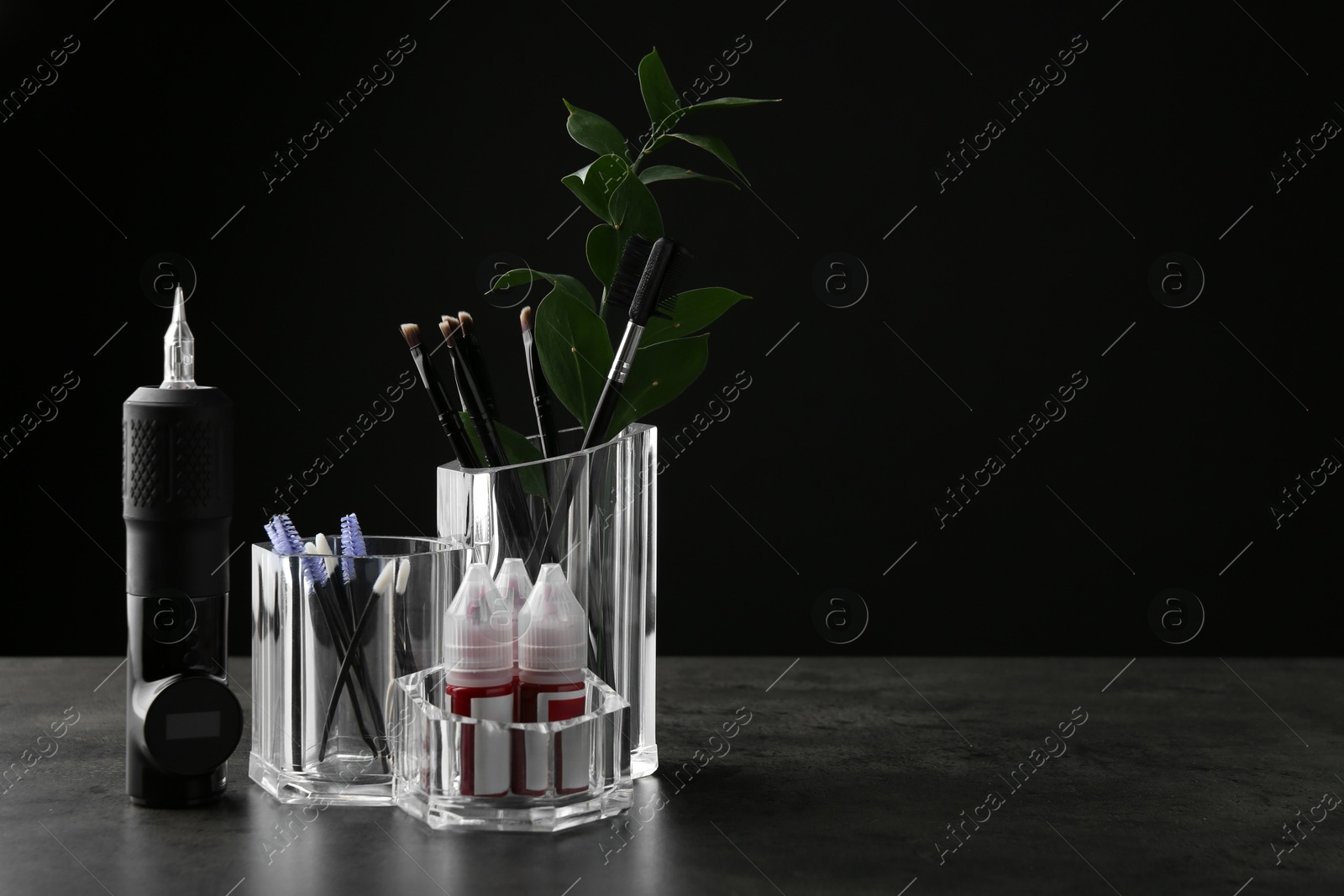 Photo of Permanent makeup equipment kit on grey table. Space for text