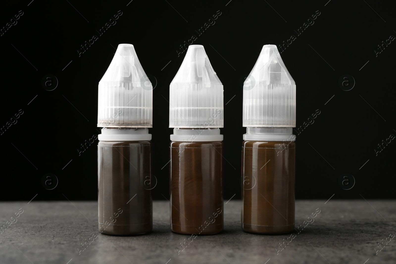 Photo of Bottles of pigments for permanent makeup on grey table