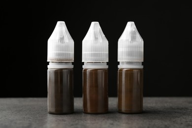 Bottles of pigments for permanent makeup on grey table