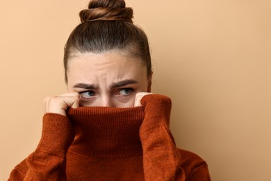 Photo of Scared young woman hiding on beige background