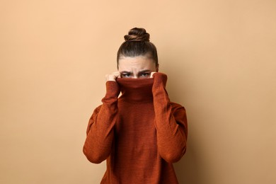 Photo of Scared young woman hiding on beige background