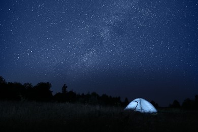 Photo of Modern camping tent in wilderness at night