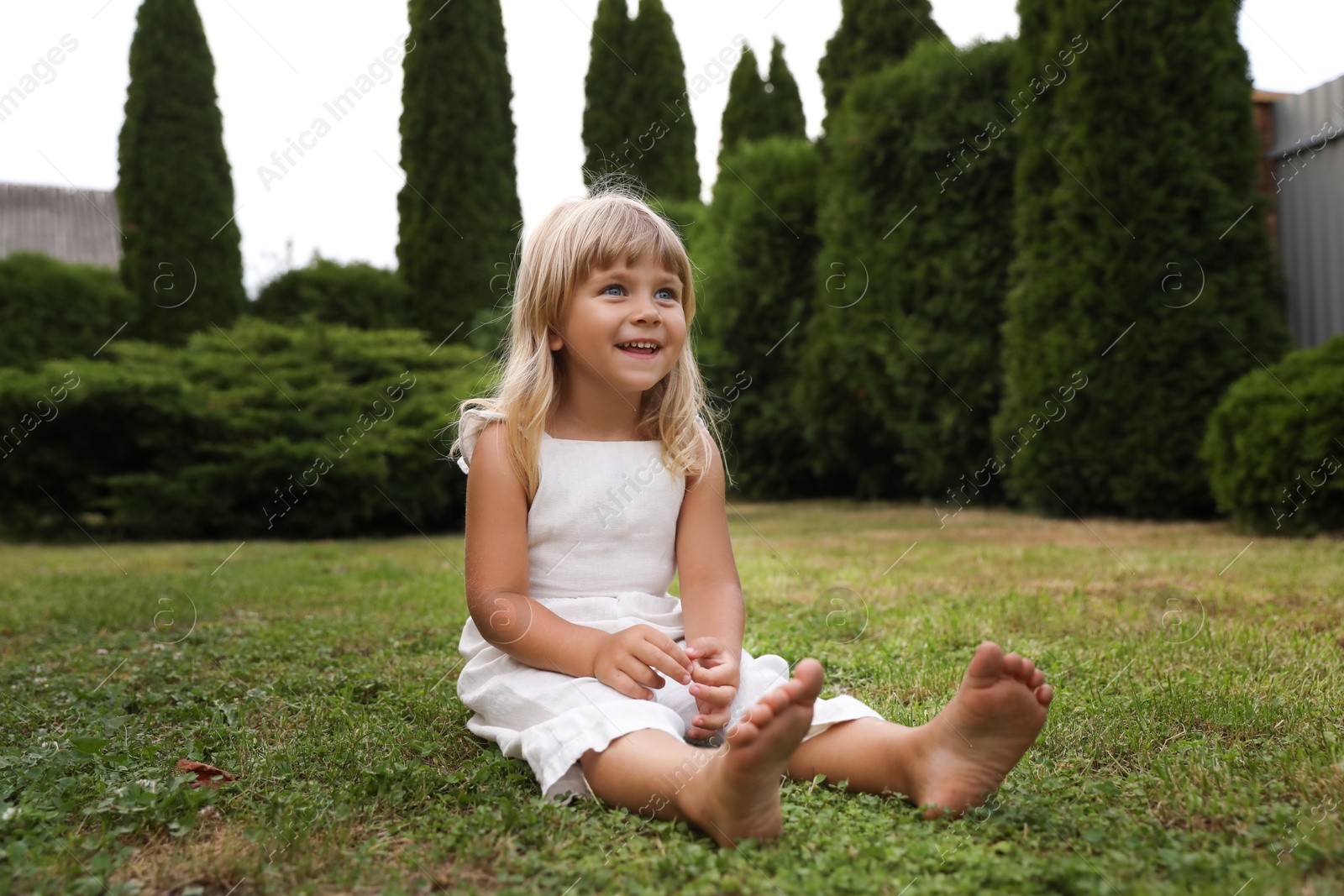 Photo of Barefoot little girl on green grass outdoors. Child enjoying beautiful nature