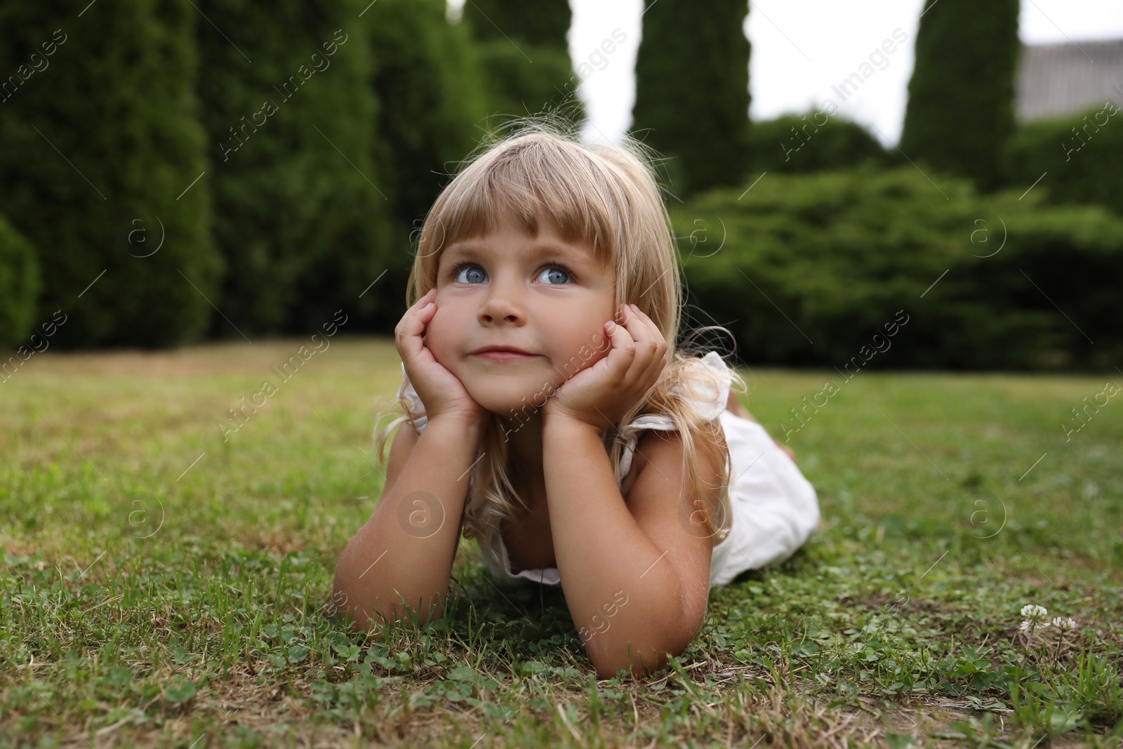 Photo of Cute little girl on green grass outdoors. Child enjoying beautiful nature