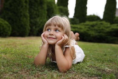 Photo of Cute little girl on green grass outdoors. Child enjoying beautiful nature