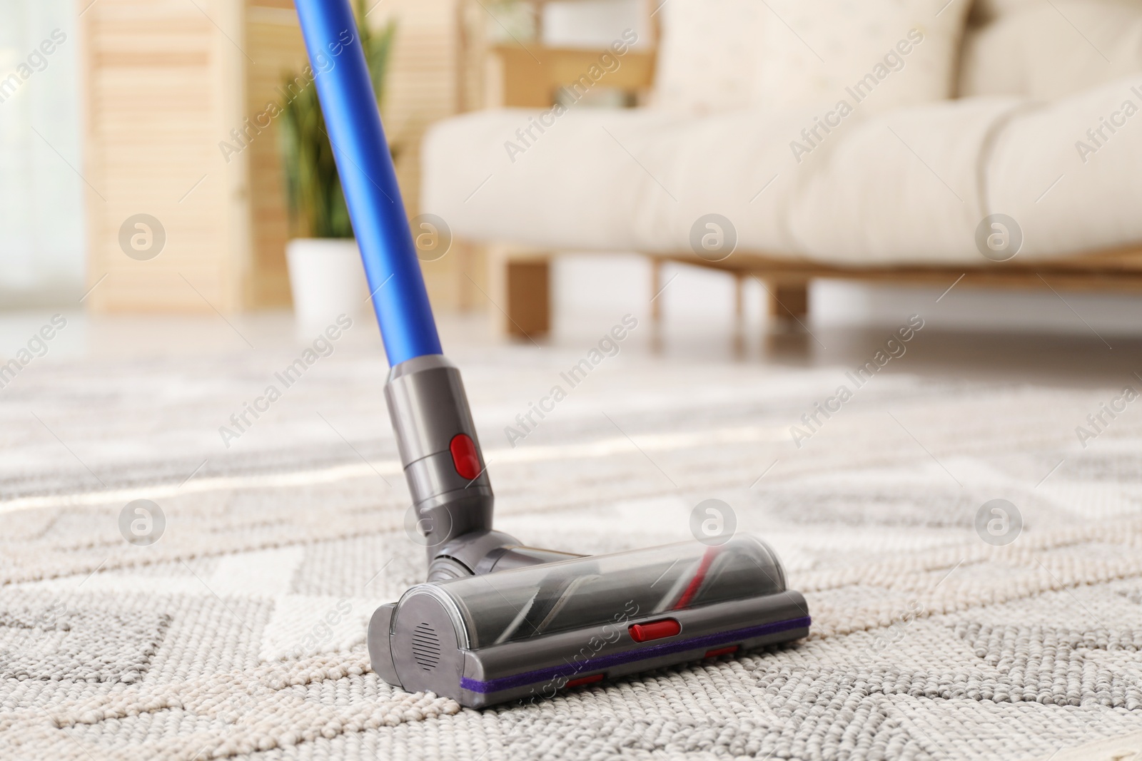 Photo of Cleaning with wireless handheld vacuum cleaner indoors, closeup