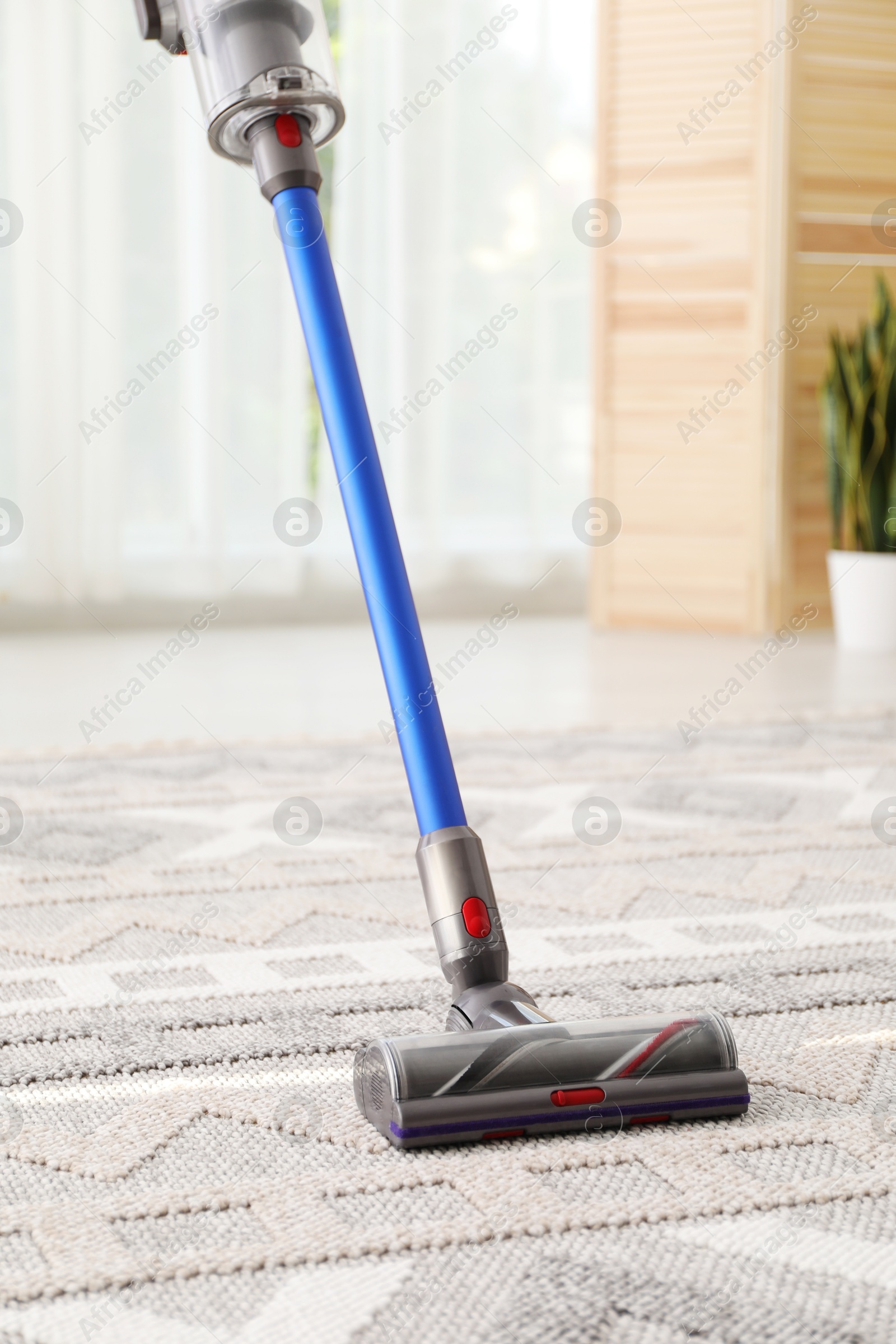 Photo of Cleaning with wireless handheld vacuum cleaner indoors, closeup