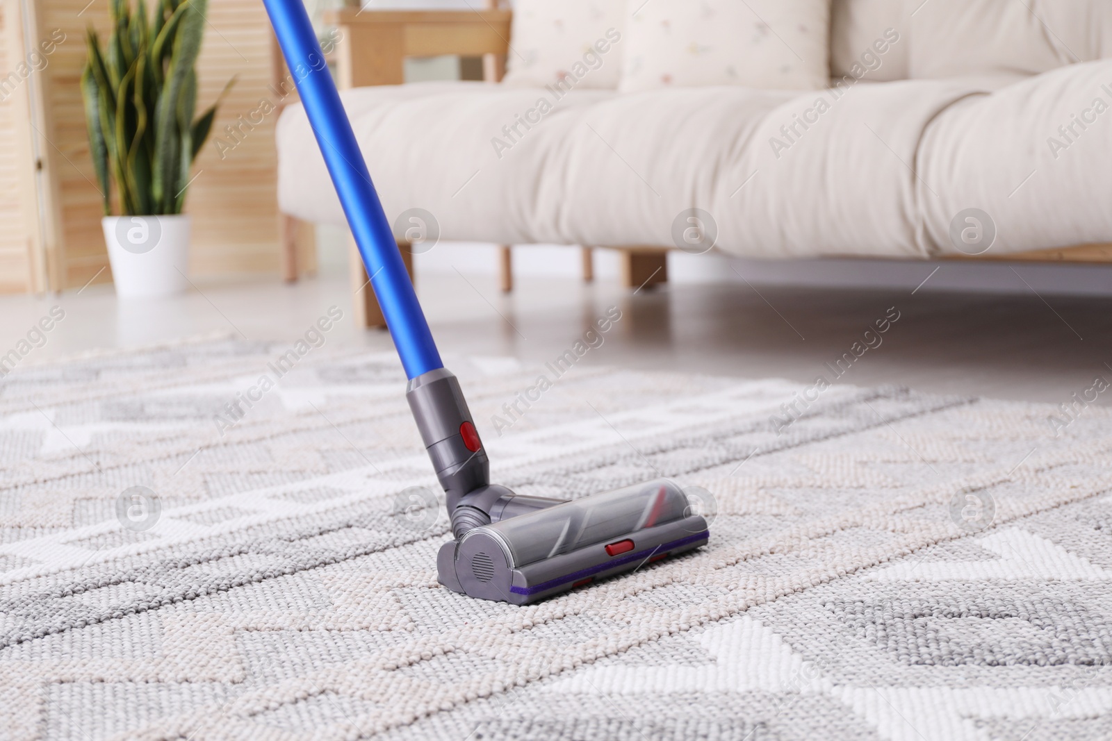 Photo of Cleaning with wireless handheld vacuum cleaner indoors, closeup