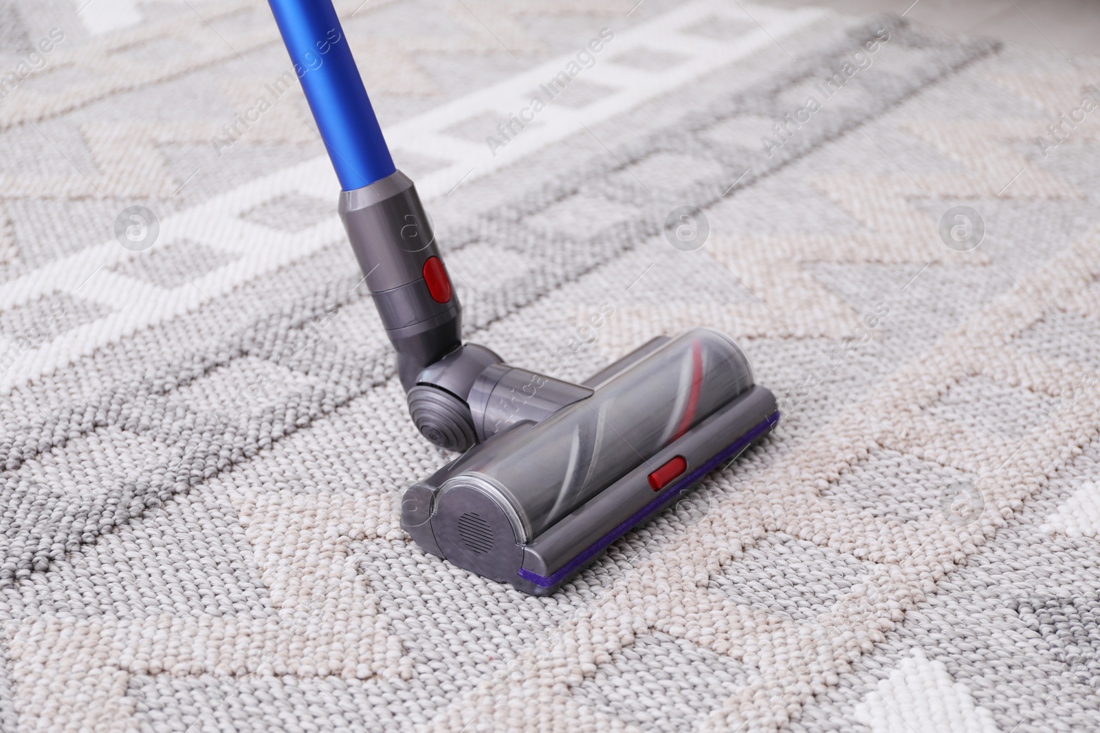 Photo of Cleaning rug with wireless handheld vacuum, closeup