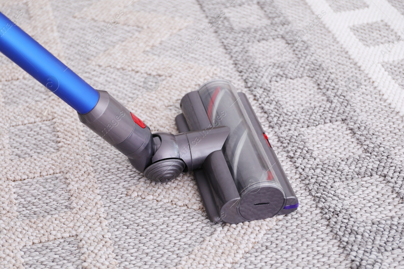 Photo of Cleaning rug with wireless handheld vacuum, closeup