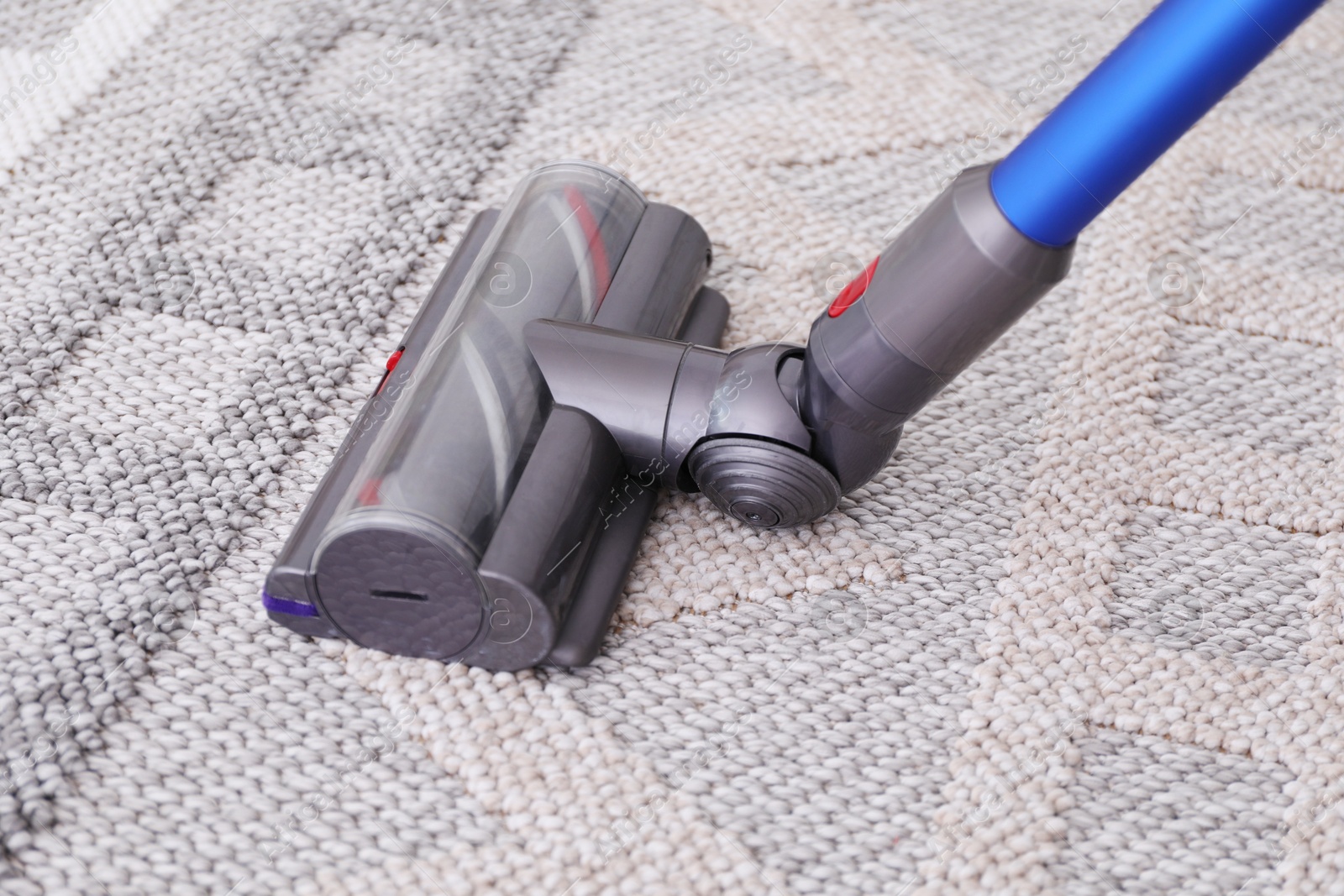 Photo of Cleaning rug with wireless handheld vacuum, closeup