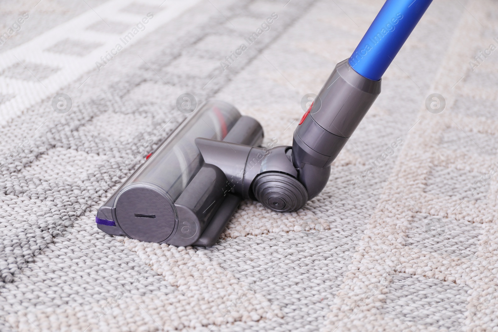 Photo of Cleaning rug with wireless handheld vacuum, closeup