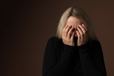 Photo of Portrait of scared woman on brown background, space for text