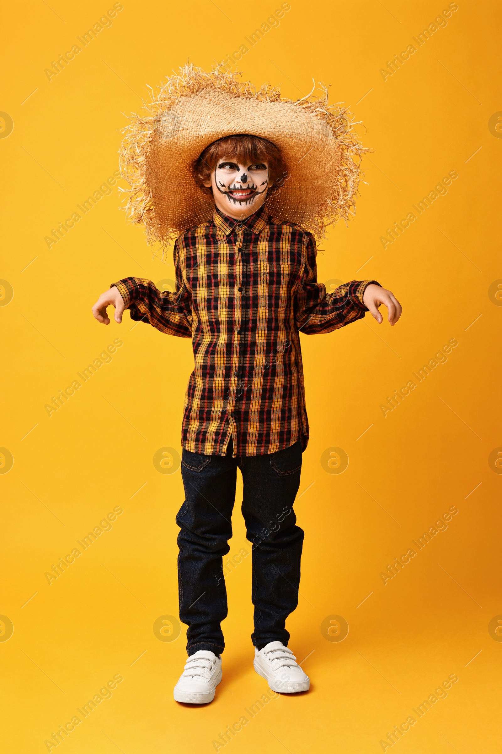 Photo of Funny boy dressed like scarecrow on yellow background. Halloween celebration