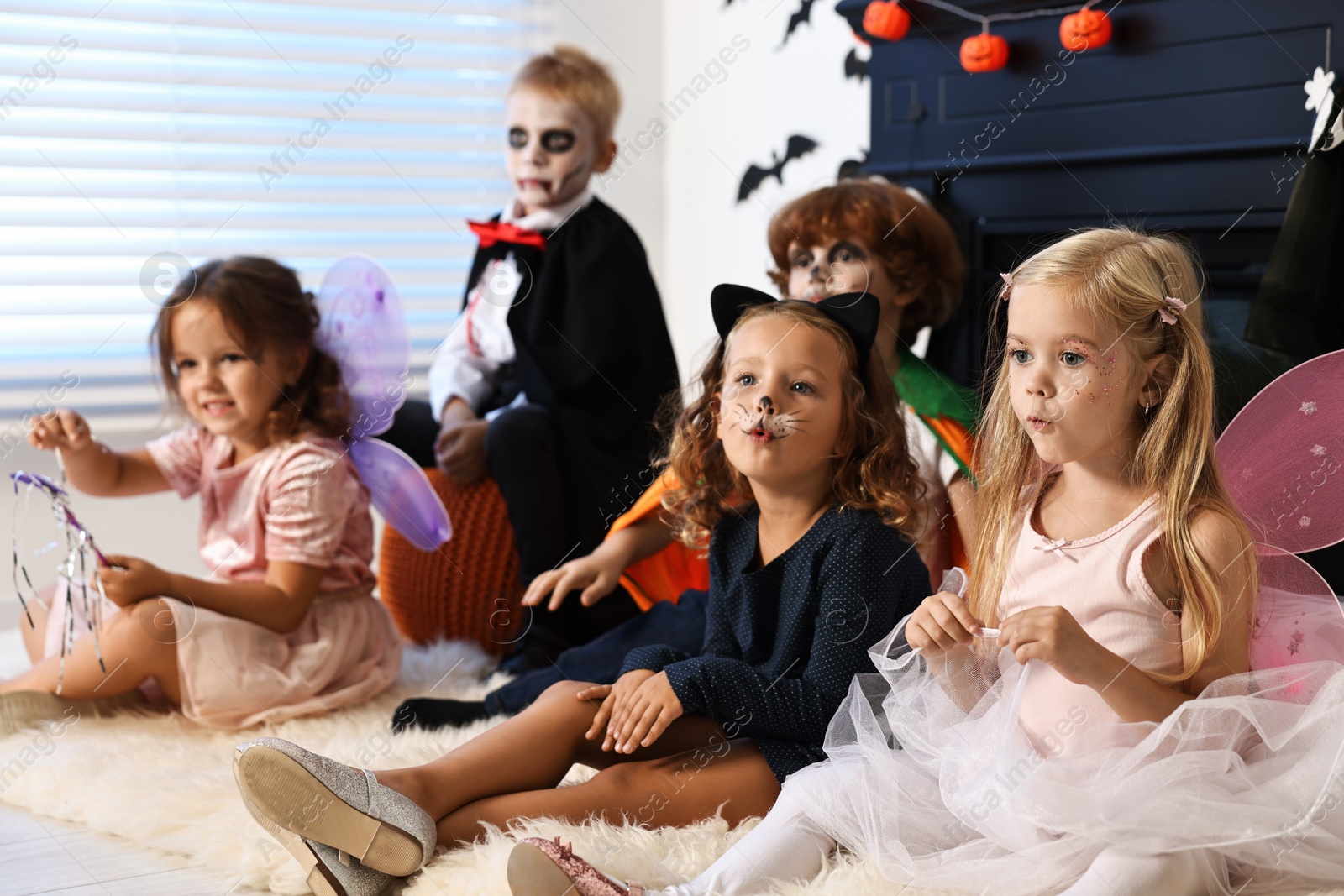 Photo of Funny children wearing costumes for Halloween celebration indoors, selective focus