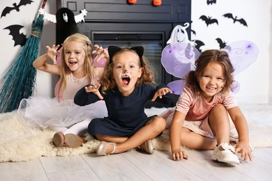 Photo of Cute girls wearing costumes for Halloween celebration in room