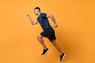 Man in sportswear running on orange background