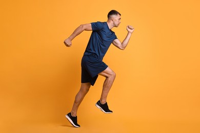 Photo of Man in sportswear running on orange background