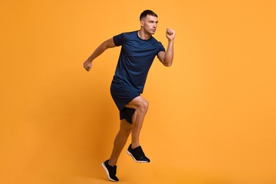 Photo of Man in sportswear running on orange background