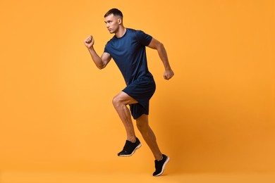 Photo of Man in sportswear running on orange background