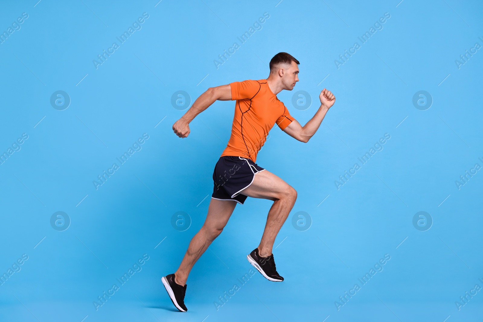 Photo of Man in sportswear running on light blue background