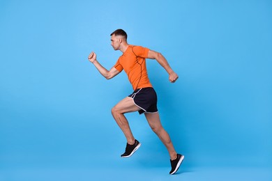 Photo of Man in sportswear running on light blue background