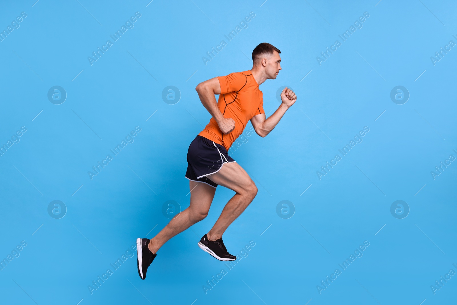 Photo of Man in sportswear running on light blue background