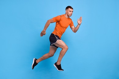 Photo of Man in sportswear running on light blue background