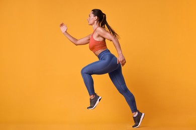 Woman in sportswear running on orange background