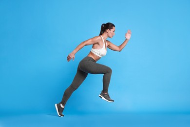 Photo of Woman in sportswear running on light blue background