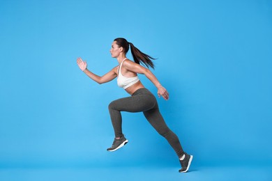 Photo of Woman in sportswear running on light blue background