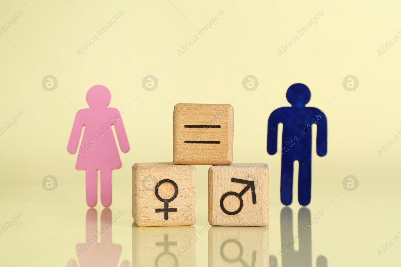 Photo of Gender equality concept. Wooden cubes with male and female figures on light yellow background