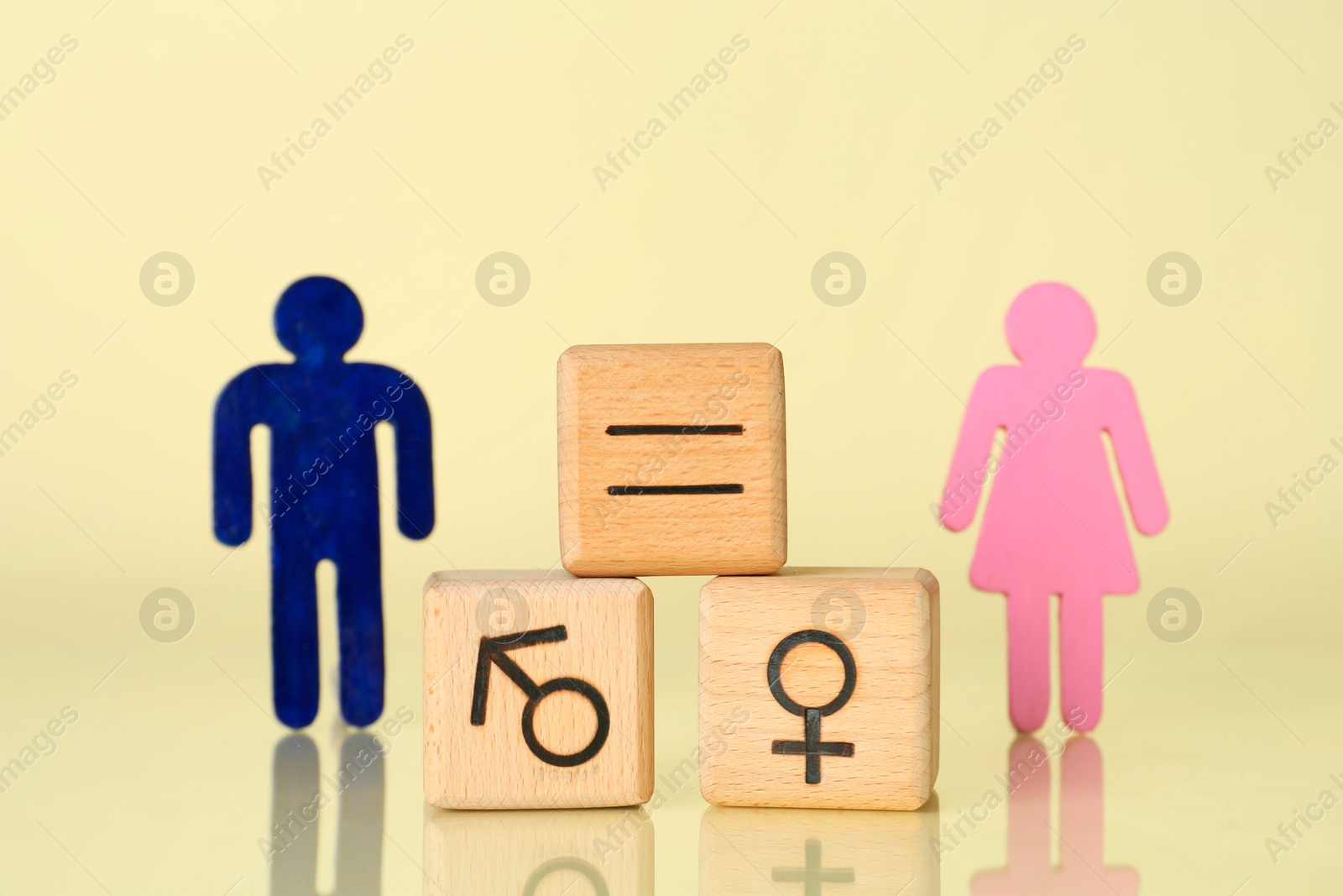 Photo of Gender equality concept. Wooden cubes with male and female figures on light yellow background