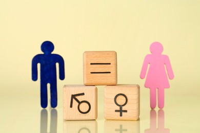 Photo of Gender equality concept. Wooden cubes with male and female figures on light yellow background