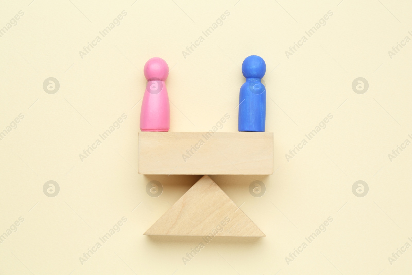 Photo of Gender equality concept. Male and female figures on scales against beige background, flat lay