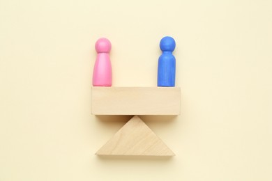 Gender equality concept. Male and female figures on scales against beige background, flat lay