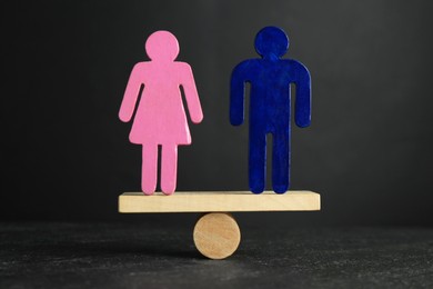 Gender equality concept. Male and female figures on scales against grey background