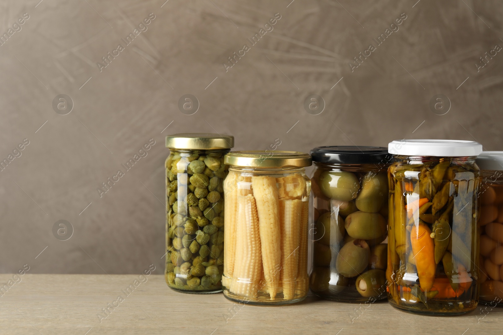 Photo of Different pickled products in jars on wooden table