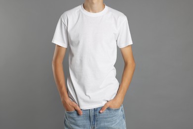 Teenage boy wearing white t-shirt on grey background, closeup