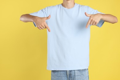 Photo of Teenage boy wearing light blue t-shirt on yellow background, closeup