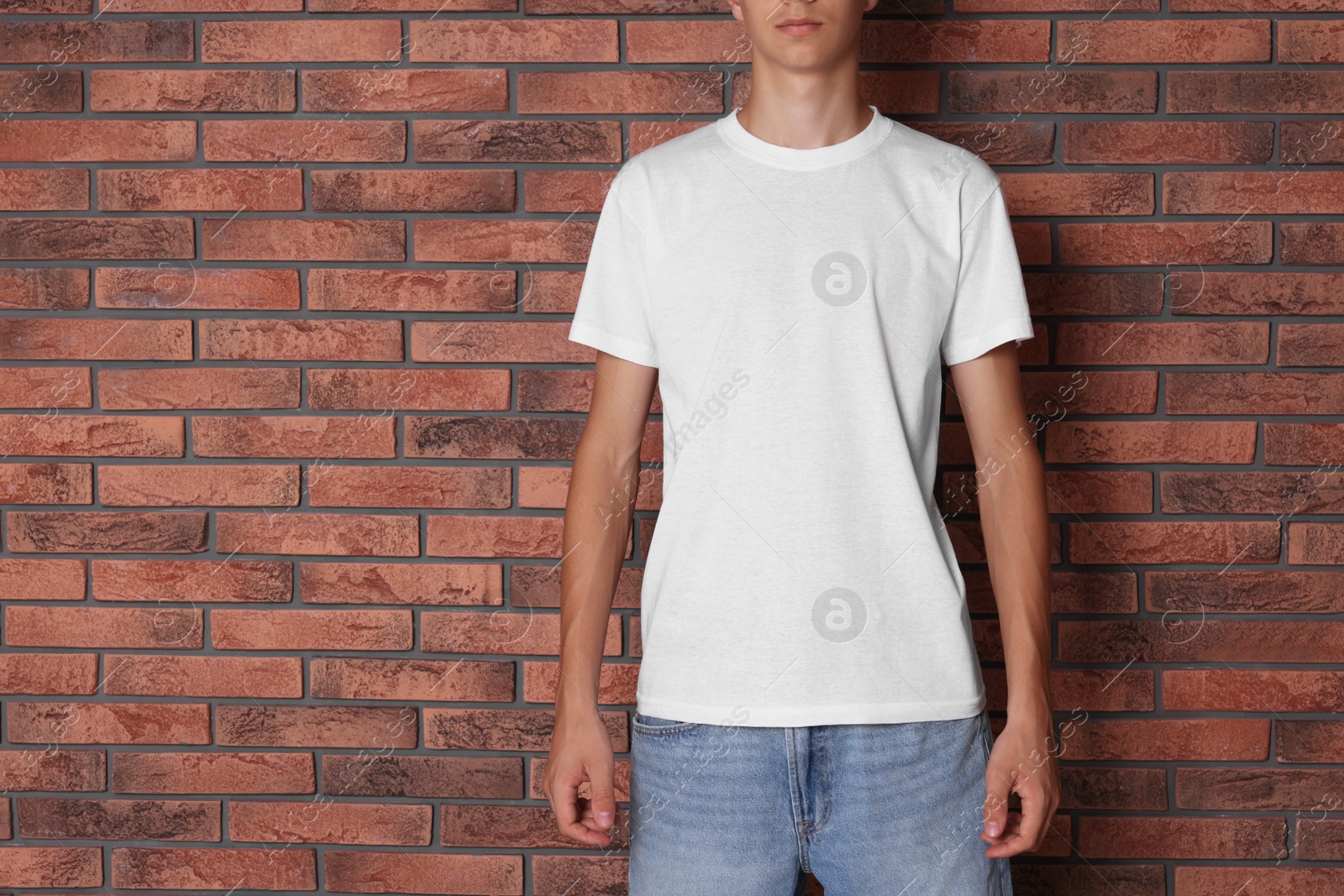 Photo of Teenage boy wearing white t-shirt near brick wall, closeup. Space for text