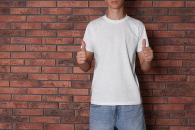 Teenage boy wearing white t-shirt near brick wall, closeup