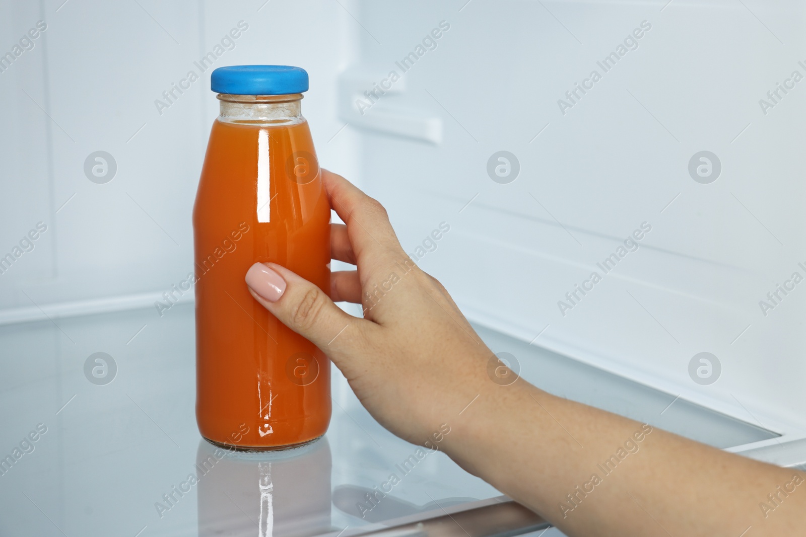 Photo of Woman taking bottle of juice from refrigerator, closeup