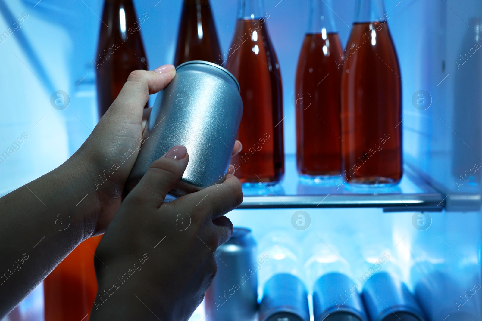 Photo of Woman taking can of beer from refrigerator, closeup