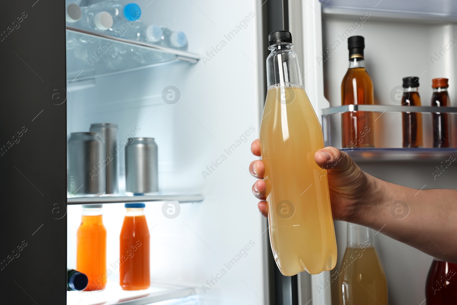 Photo of Woman taking bottle with drink from refrigerator, closeup