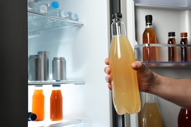 Photo of Woman taking bottle with drink from refrigerator, closeup