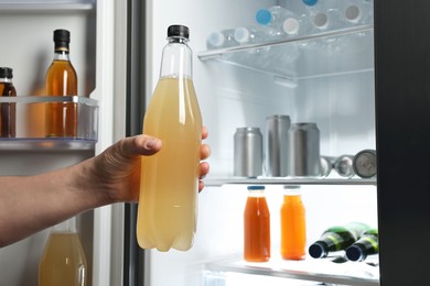 Photo of Woman taking bottle with drink from refrigerator, closeup